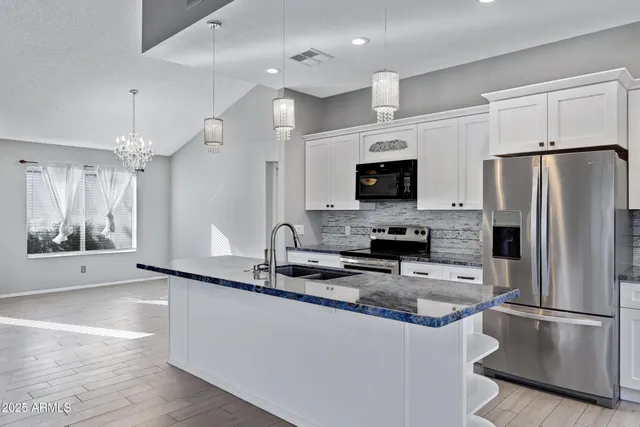 a kitchen with stainless steel appliances granite countertop a refrigerator a stove a sink and a microwave