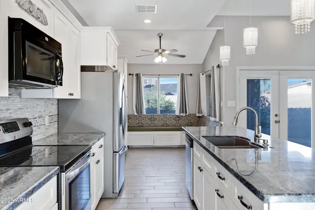 a kitchen with granite countertop a sink a counter top space appliances and cabinets