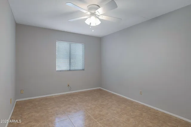 an empty room with windows and ceiling fan
