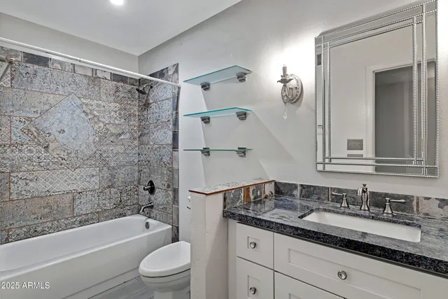 a bathroom with a granite countertop sink a toilet and a bathtub