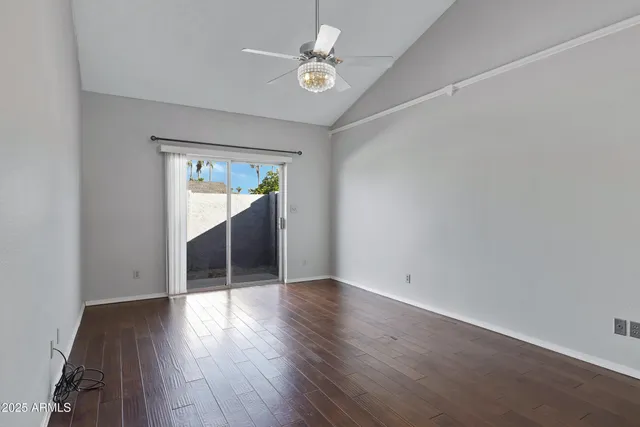 an empty room with wooden floor and ceiling fan