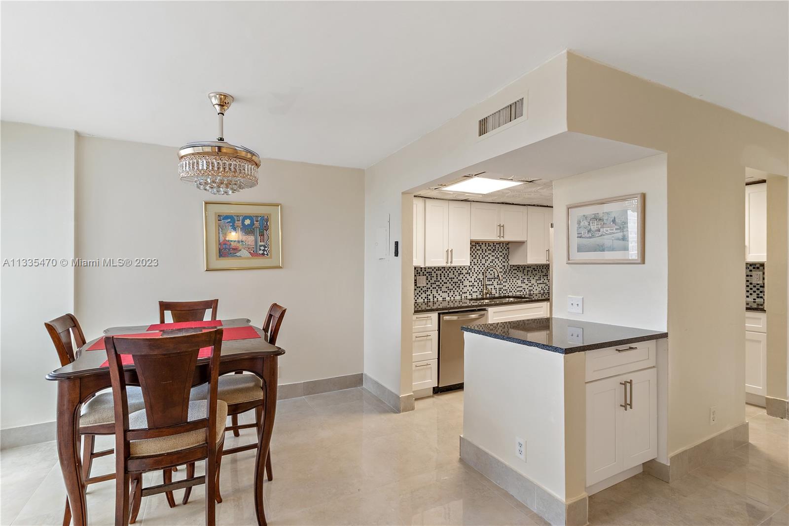 a kitchen with stainless steel appliances kitchen island granite countertop a dining table chairs and a refrigerator