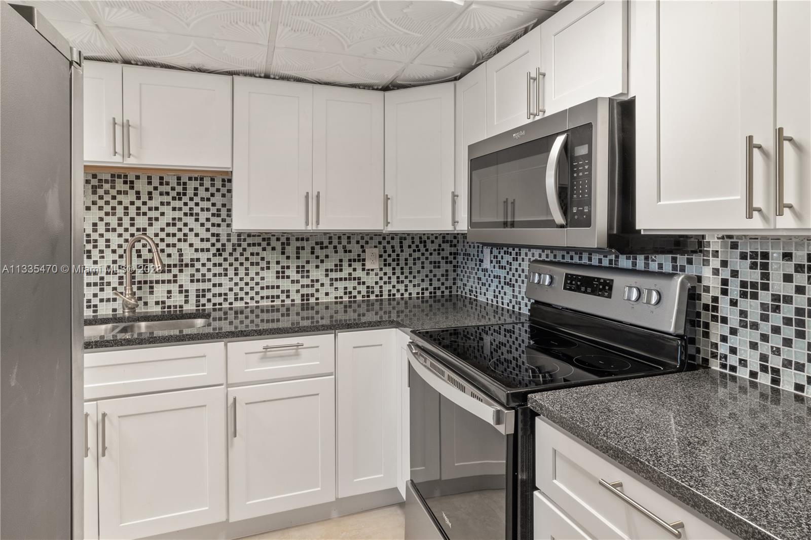 1401 South Federal Highway, Unit 204 Boca Raton, FL 33432 - Photo 4 of 22 a kitchen with granite countertop white cabinets and black appliances