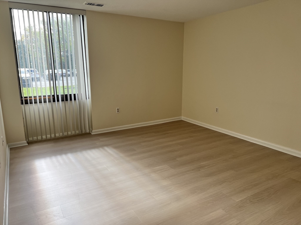 1002 Paradise Road, Unit 1M Swampscott, MA 01907 - Photo 13 of 25 an empty room with wooden floor and windows