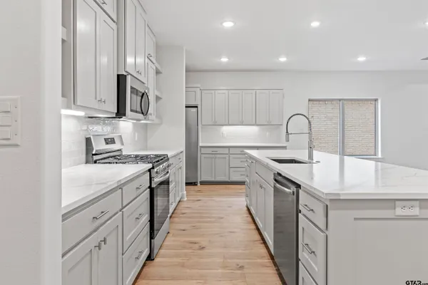 a large kitchen with stainless steel appliances granite countertop a lot of counter space and wooden floor