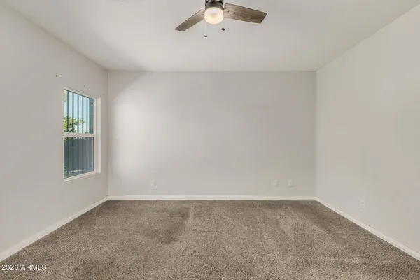 an empty room with windows and chandelier fan