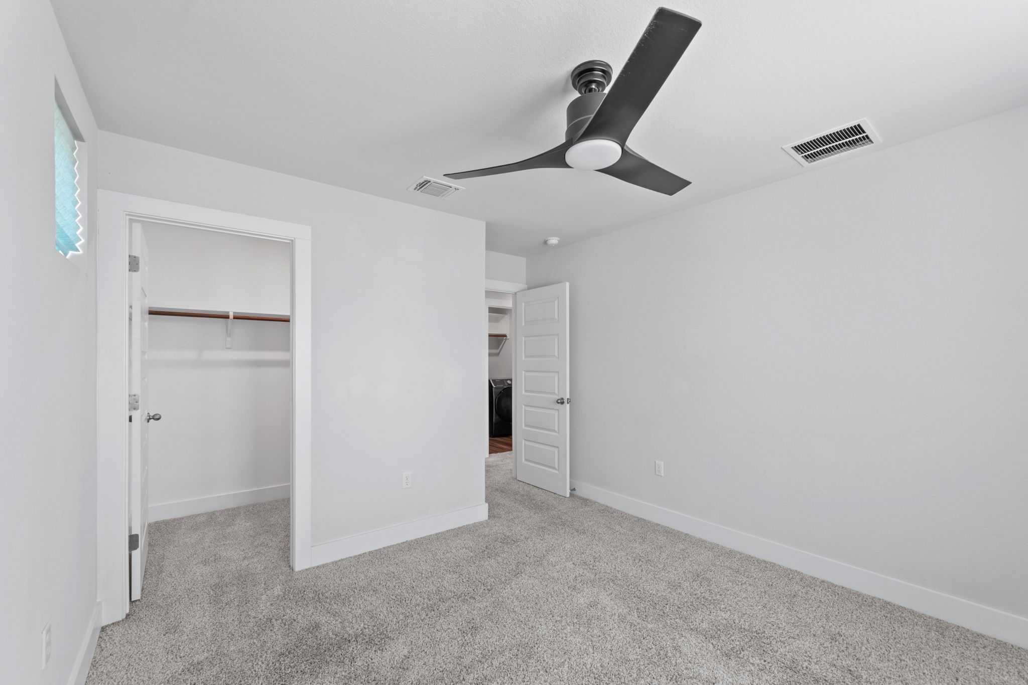 7312 Travertine Spring Drive Austin, TX 78744 - Photo 29 of 32 A well-lit bedroom features plush carpeting and a modern ceiling fan, offering a comfortable personal retreat.
