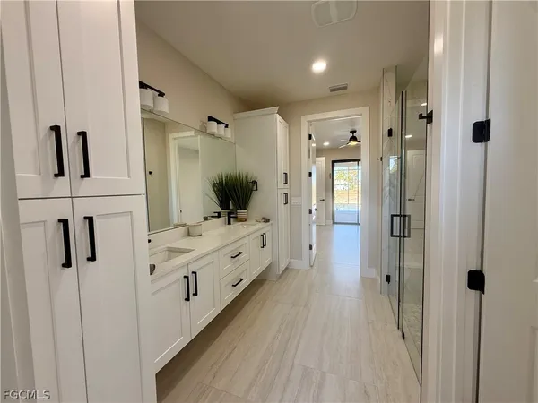 a bathroom with a glass door shower a sink and mirror
