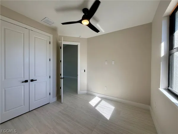 an empty room with wooden floor cabinet and windows