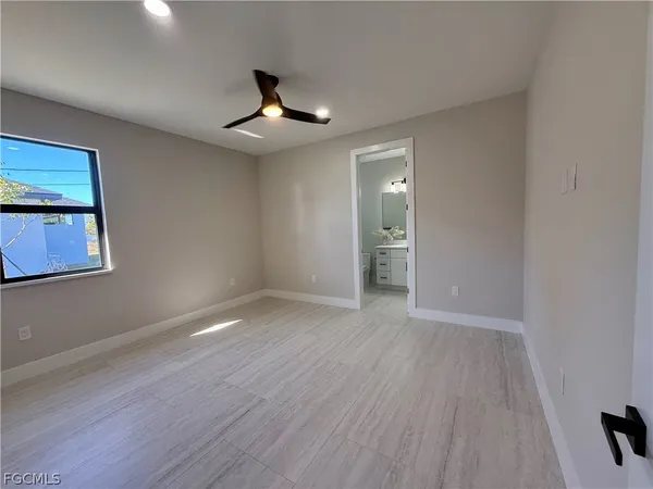 a view of an empty room with wooden floor and a ceiling fan