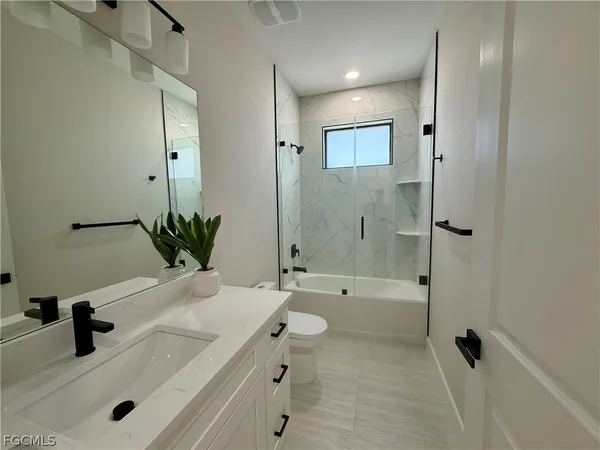 a bathroom with a granite countertop sink a toilet and shower