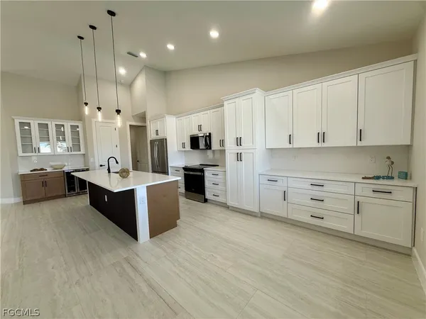 a large white kitchen with cabinets a sink and appliances
