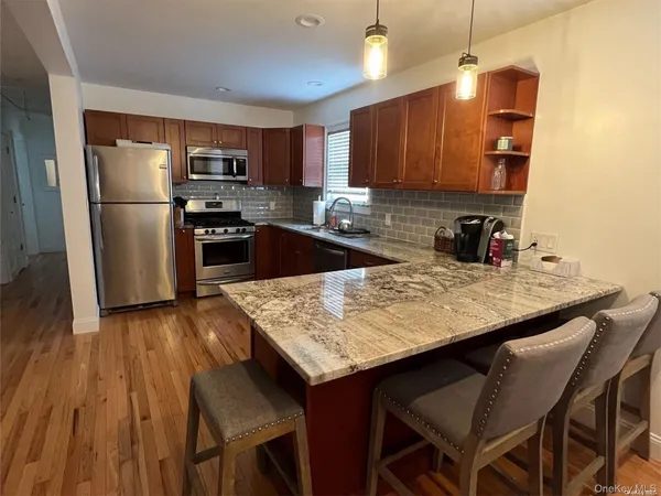 a kitchen with granite countertop a wooden floor and refrigerator