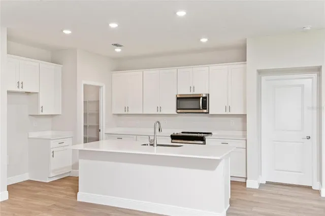 a kitchen with stainless steel appliances a stove a sink and white cabinets