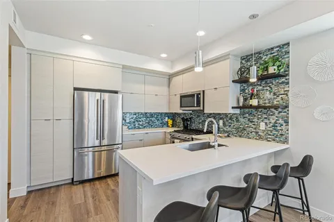a kitchen with stainless steel appliances a dining table chairs and refrigerator