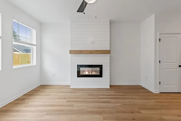 a view of an empty room with wooden floor and a window