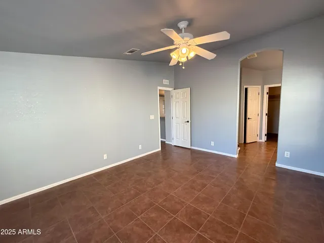 a view of an empty room and chandelier fan