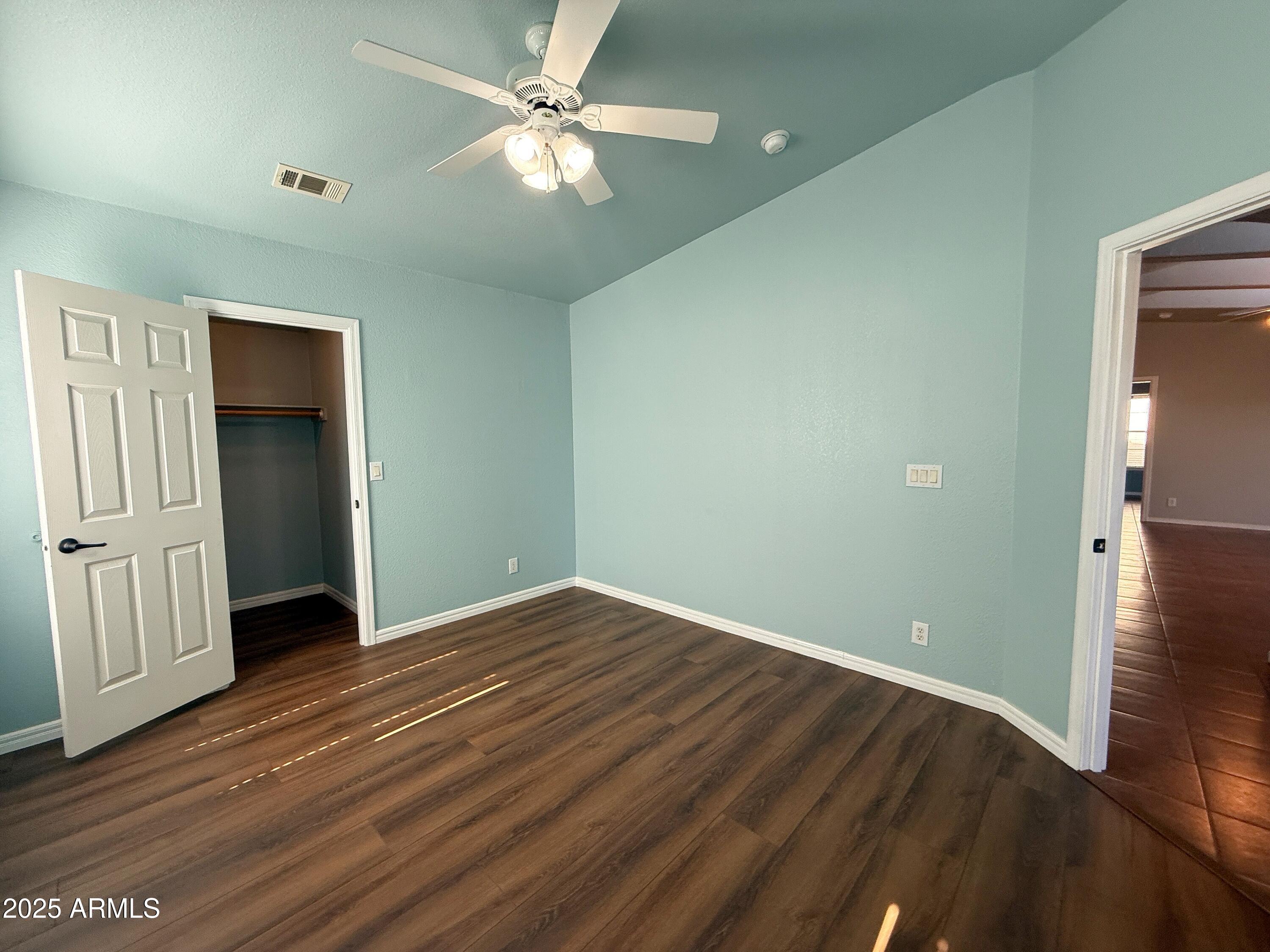 3301 South Goldfield Road, Unit 5078 Apache Junction, AZ 85119 - Photo 25 of 46 an empty room with wooden floor chandelier fan and windows