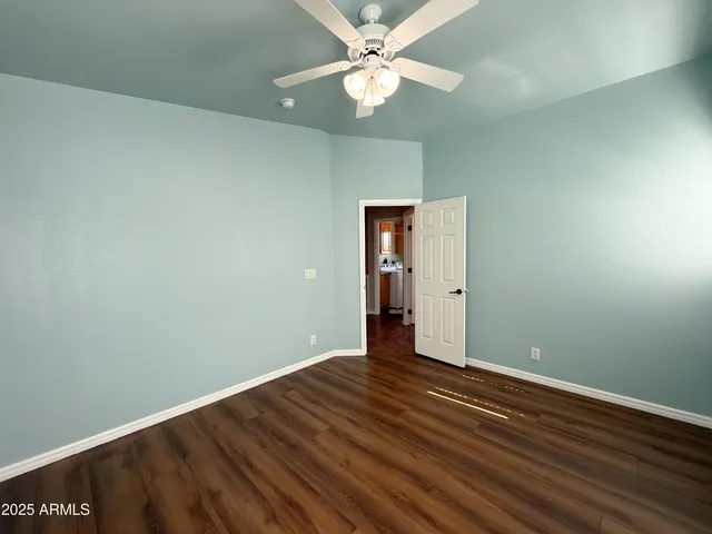 an empty room with wooden floor a ceiling fan & windows