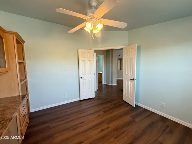 an empty room with wooden floor and a ceiling fan