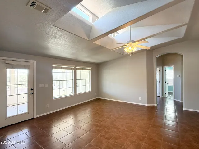 a view of an empty room with window and wooden floor
