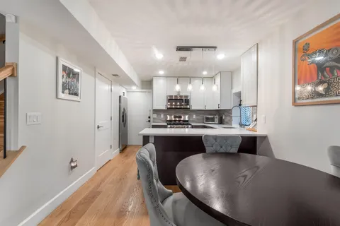 a large white kitchen with wooden floors and stainless steel appliances