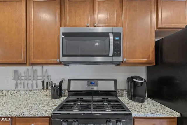 a kitchen with granite countertop stainless steel appliances stove top oven and cabinets