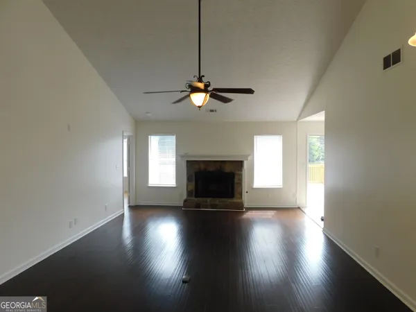 an empty room with wooden floor fireplace and windows