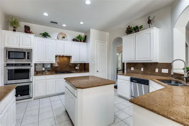 a kitchen with granite countertop a sink a counter top space appliances and cabinets