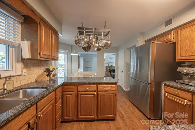 a kitchen with stainless steel appliances granite countertop a sink refrigerator and cabinets