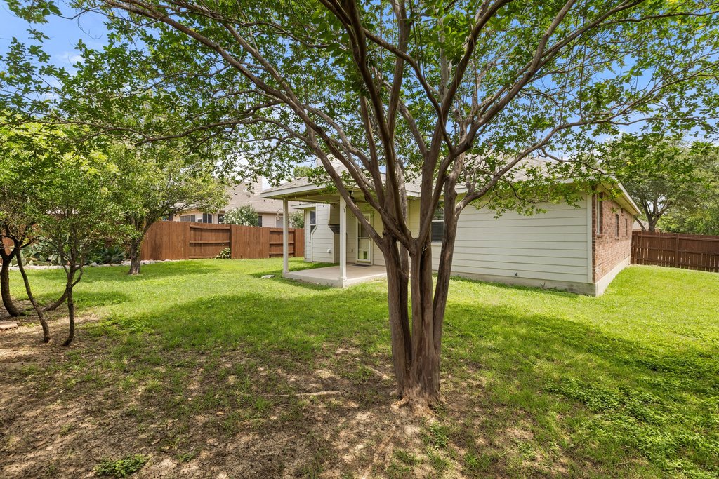 347 Spring Drive Kyle, TX 78640 - Photo 38 of 40 A spacious backyard with mature trees offers a private oasis for outdoor enjoyment.