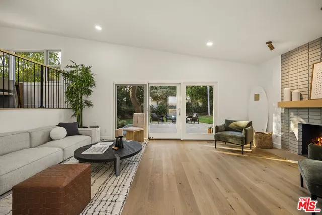 a living room with furniture a fireplace and a floor to ceiling window