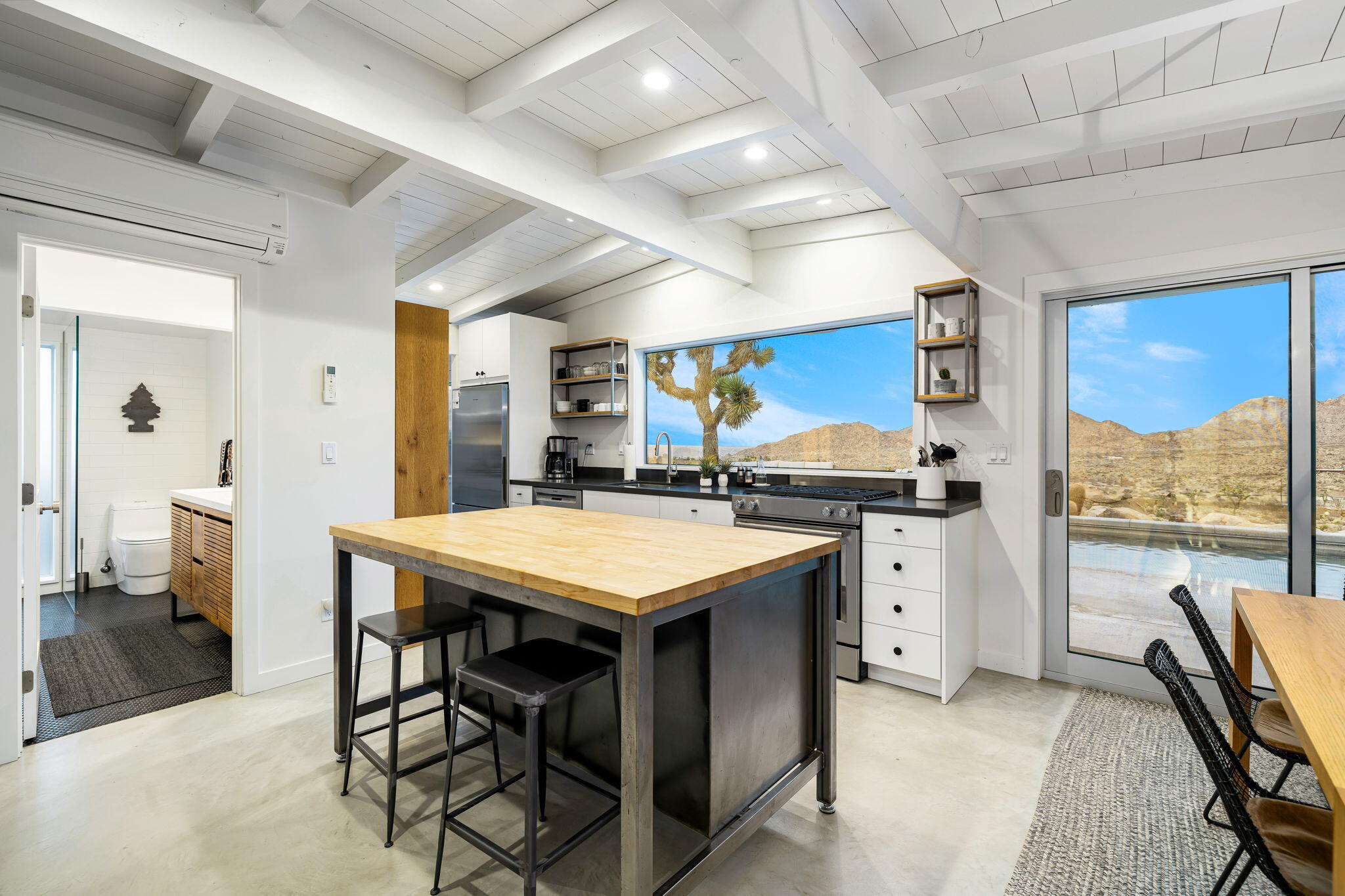 8269 Vía Rocosa Joshua Tree, CA 92252 - Photo 11 of 74 a kitchen with stainless steel appliances kitchen island granite countertop a table chairs sink and wooden cabinets