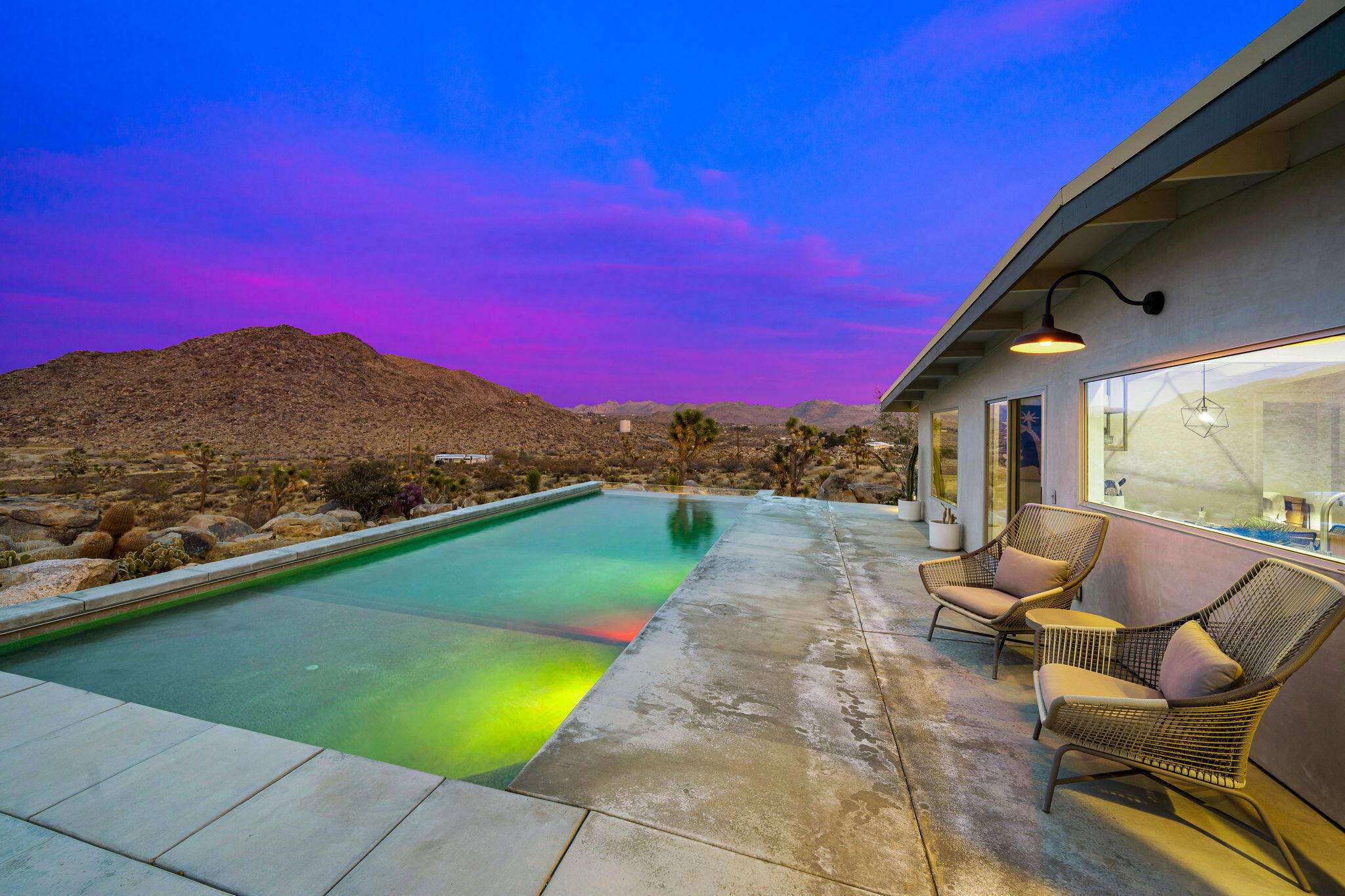 8269 Vía Rocosa Joshua Tree, CA 92252 - Photo 63 of 74 a view of a patio with couches table and chairs under an umbrella