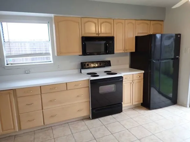 a kitchen with white cabinets a sink and a stove with refrigerator