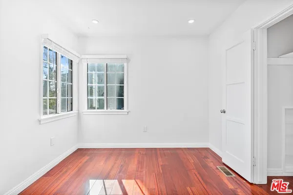 an empty room with wooden floor and windows