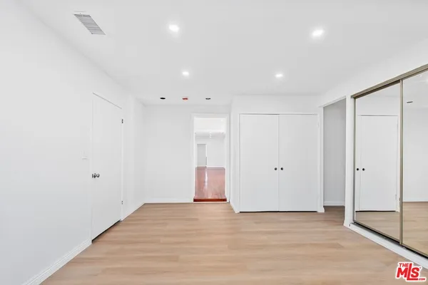 a view of an empty room with wooden floor and entryway