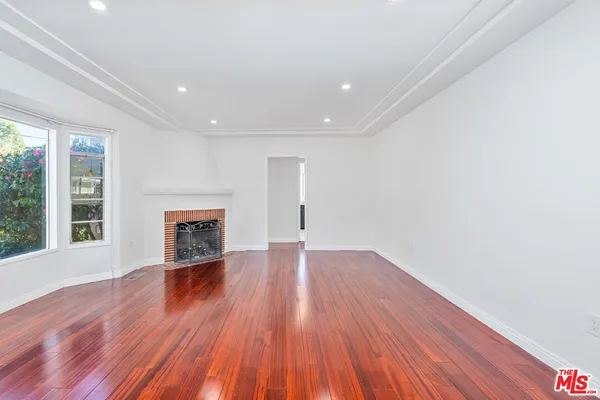 a view of empty room with wooden floor and fireplace
