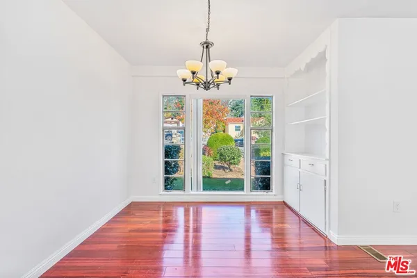 a view of a hallway with wooden floor and a chandelier