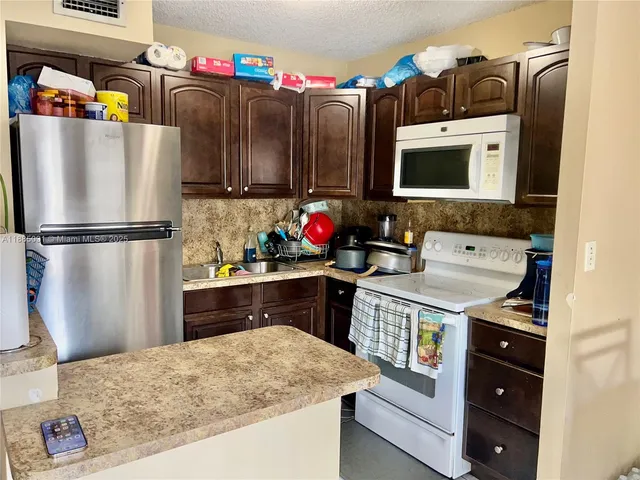 a kitchen with stainless steel appliances granite countertop a refrigerator a stove and a sink with wooden floor