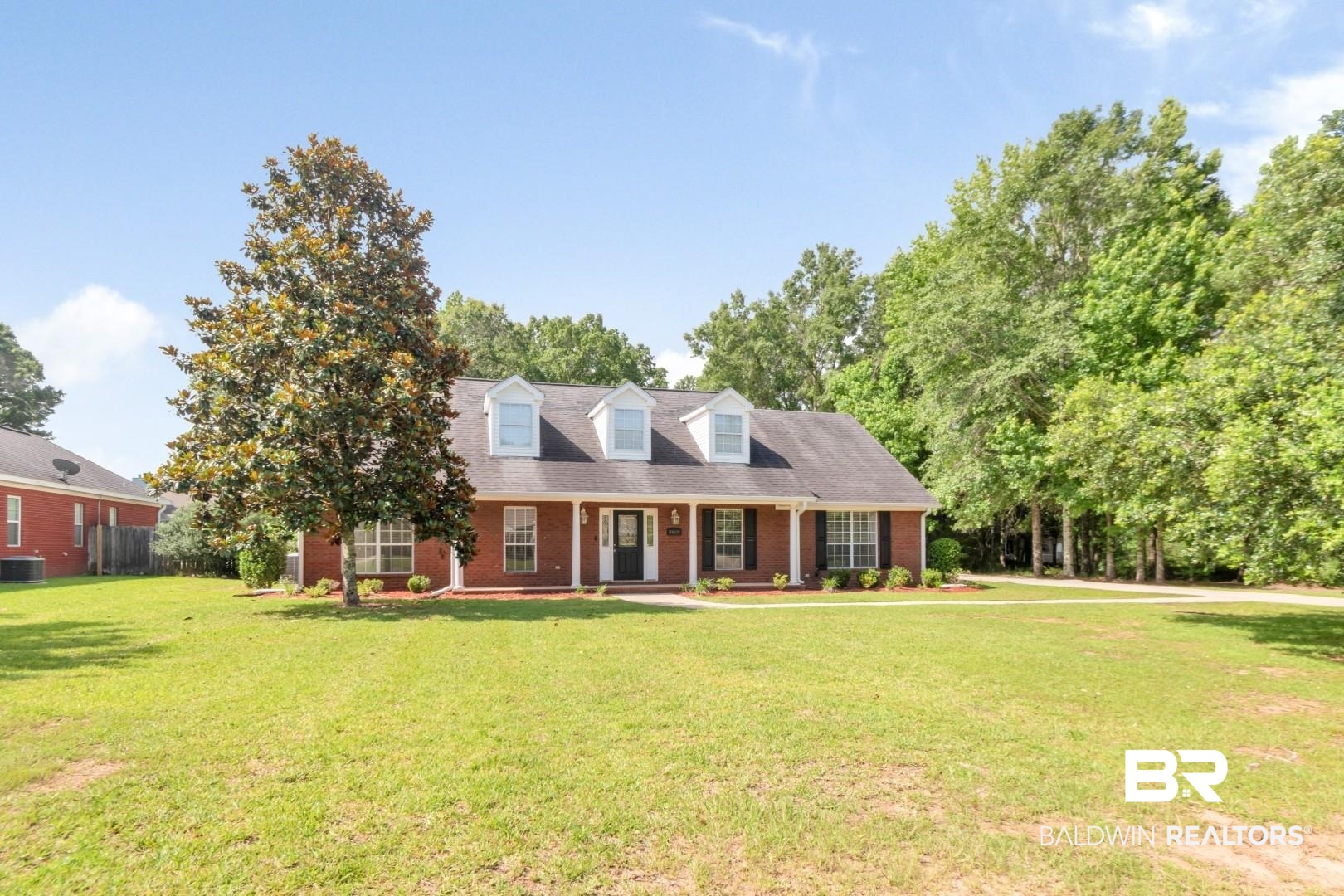 10691 Hunters Ridge Drive Mobile, AL 36695 - Photo 35 of 37 Brick exterior residence featuring a covered front porch with white columns, triple dormer windows, and a manicured front lawn