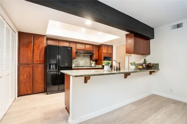 a kitchen with stainless steel appliances granite countertop a refrigerator a stove and a sink with wooden floor