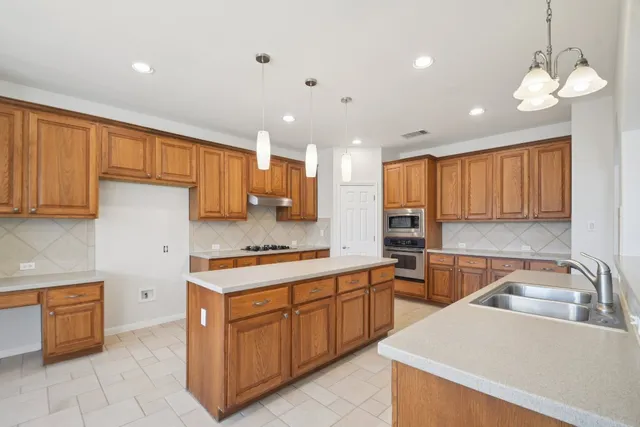 a large kitchen with kitchen island a sink stainless steel appliances and cabinets