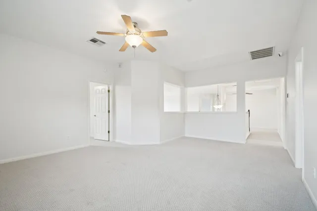 an empty room with a chandelier fan and windows