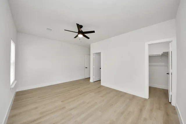 a view of empty room with wooden floor and ceiling fan