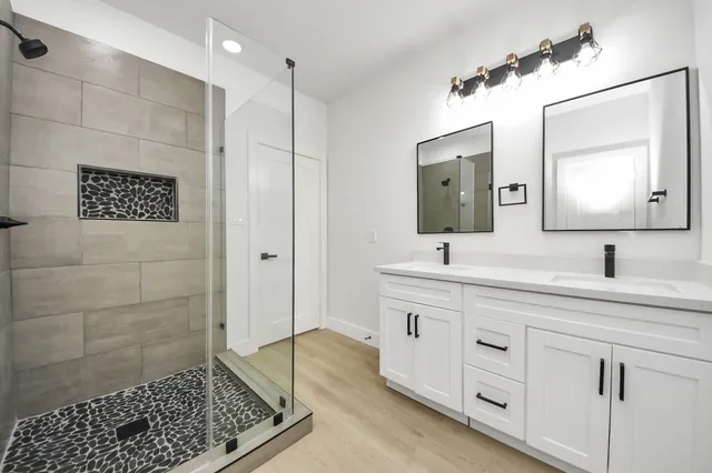 a bathroom with a double vanity sink a mirror and shower