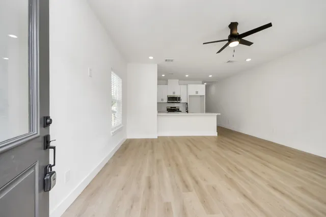 a view of a livingroom with a ceiling fan & wooden floor
