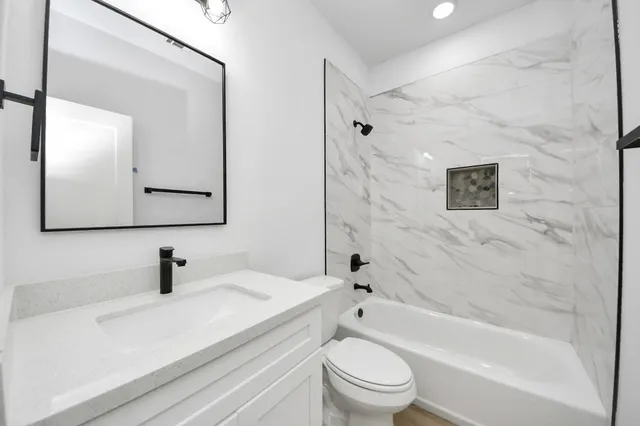 a bathroom with a sink a toilet a mirror a vanity and bathtub