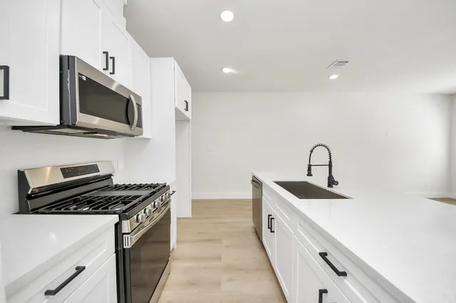 a kitchen with stainless steel appliances a sink a stove and microwave