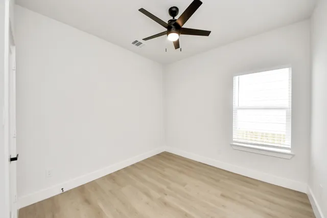 an empty room with a window and a fan
